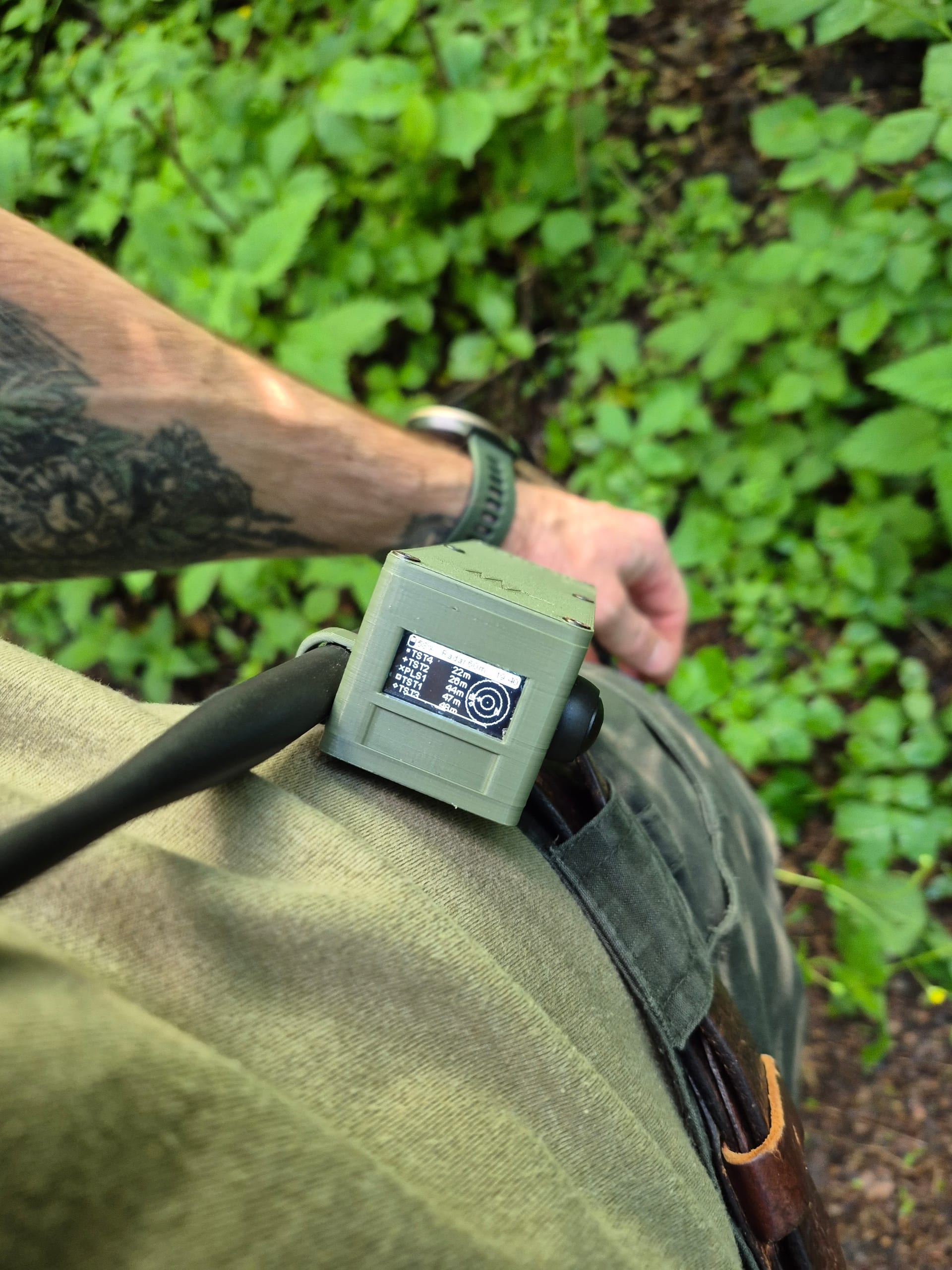 Olive RBaken on belt with radar screen lit, walking through ivy