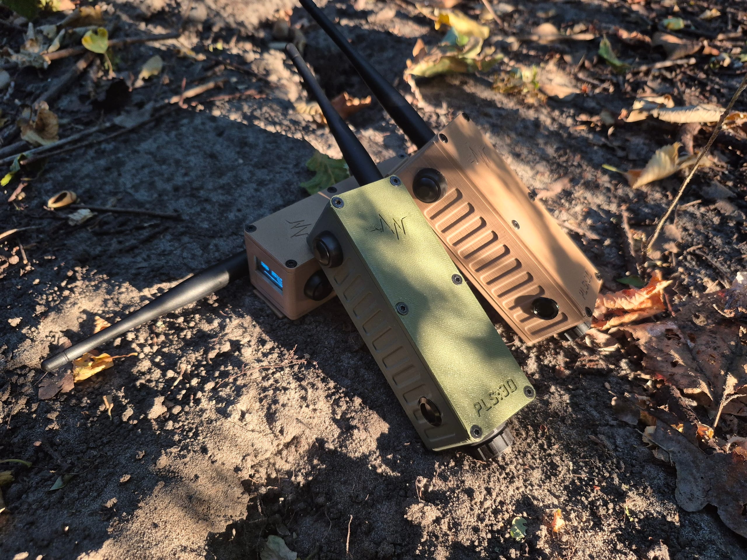 Three RBaken devices resting on forest ground among dry leaves